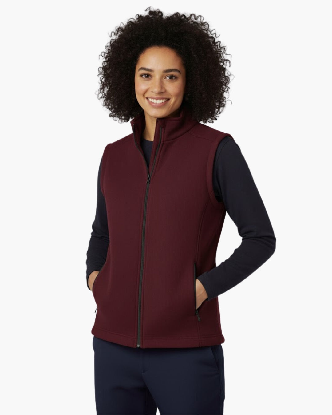 Woman wearing a maroon vest over a black long-sleeve shirt on a white background